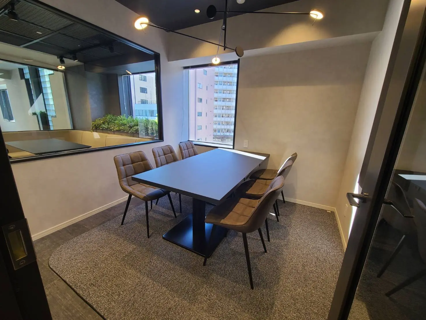 モダンな会議室のインテリア、大きな窓、ブラックのテーブルとベージュの椅子、グレーのカーペット