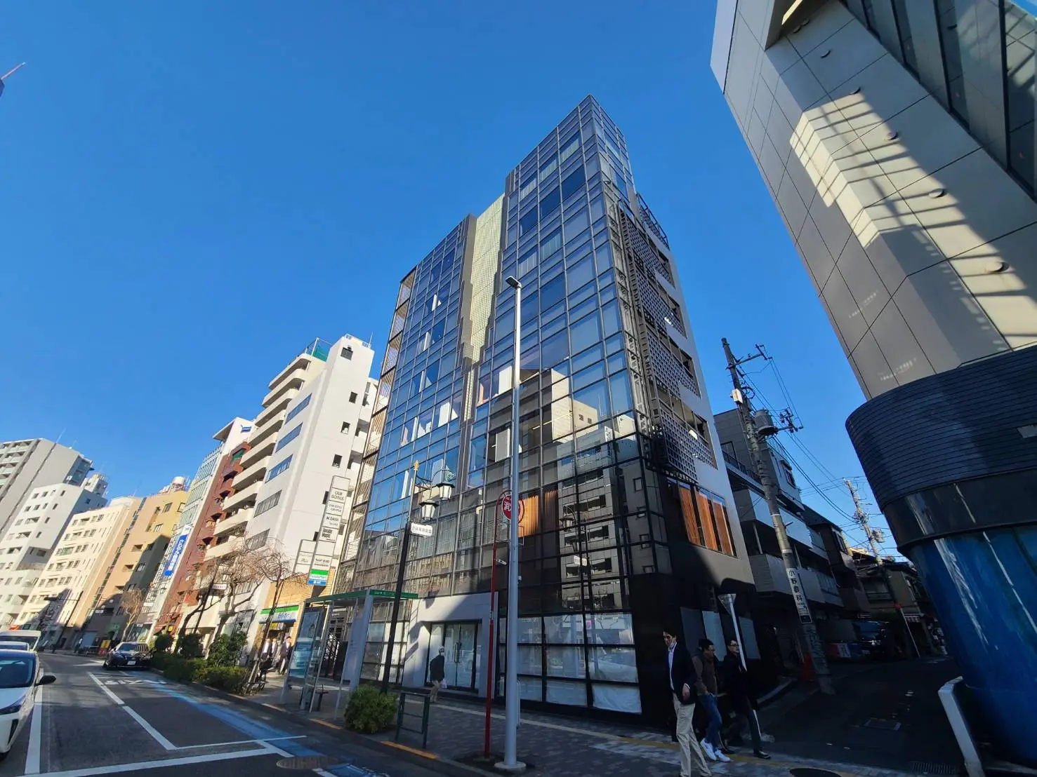 日本の都市部にある現代的なビル群、青空、歩行者のある街並み