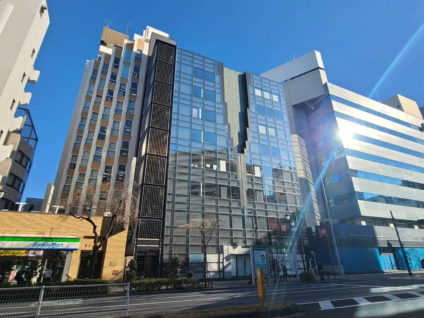 快晴の日の都会的なオフィスビル群とコンビニエンスストア、交差点と澄んだ青空