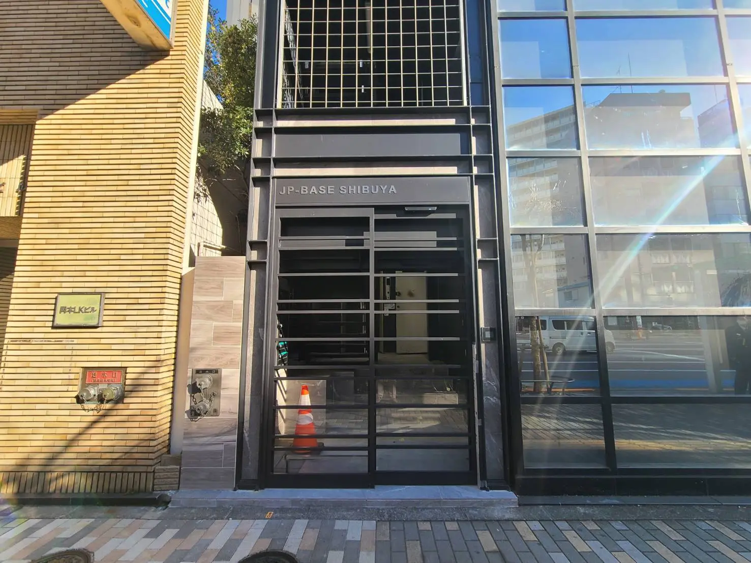 東京渋谷にあるモダンなビルの入口、ガラス扉と黒いフレームが特徴的なファサードデザイン