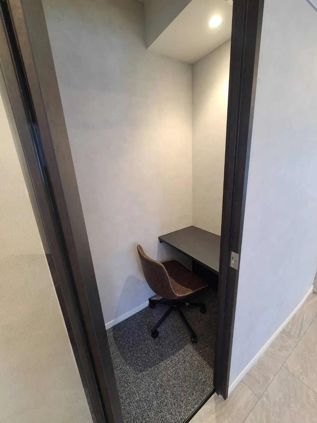 狭いスペースに最適なコンパクトなワークスペース、黒のデスクと茶色のオフィスチェア、LED照明付き