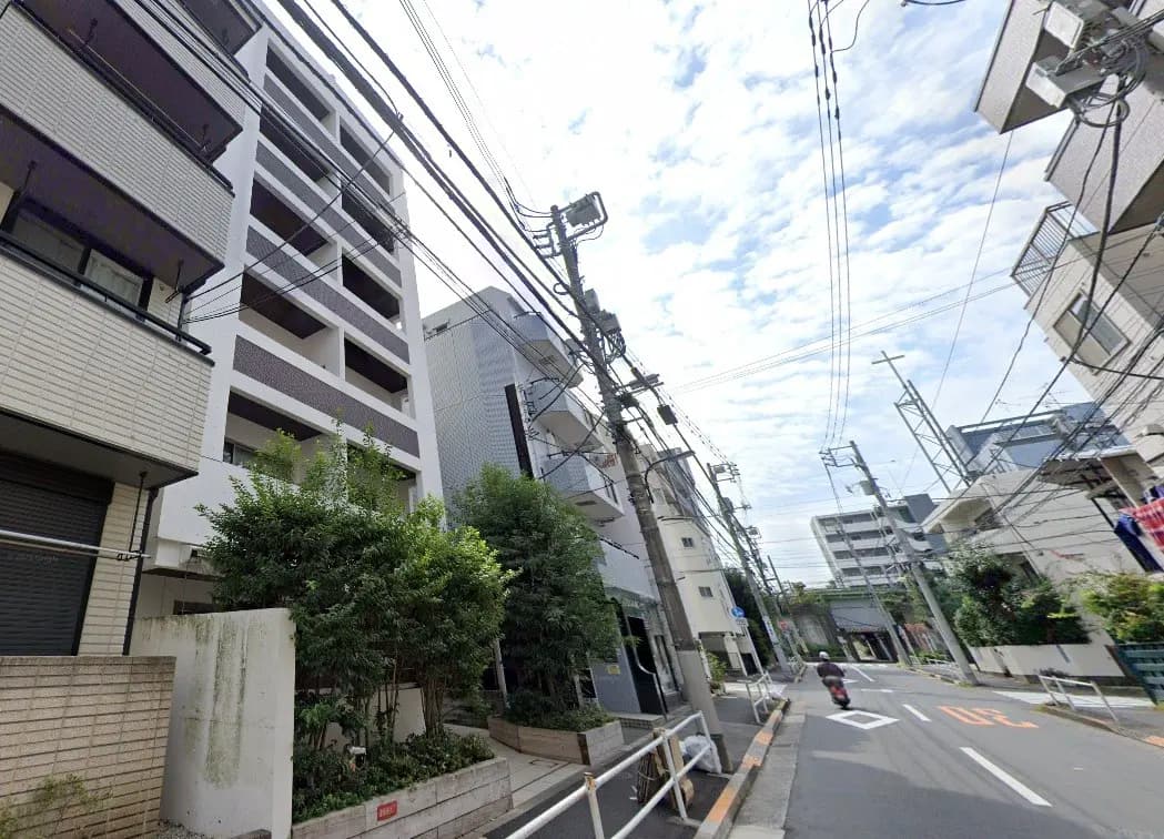 - 近代的なアパートメントビルと街路風景、緑の植栽や電線が見える都市の風景