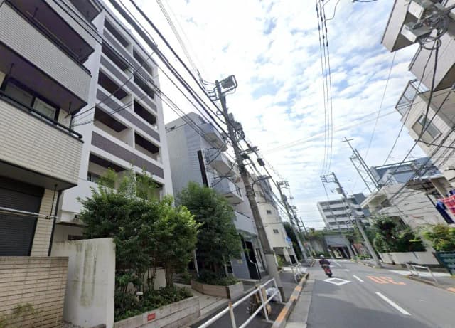 - 近代的なアパートメントビルと街路風景、緑の植栽や電線が見える都市の風景