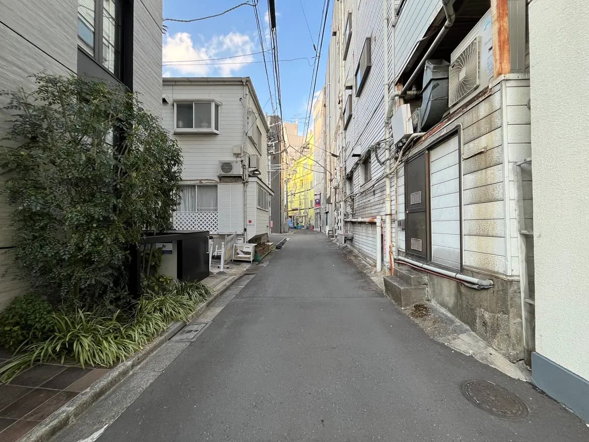 都市の狭い路地、昼間の日本の住宅街、建物とアスファルトの道路
