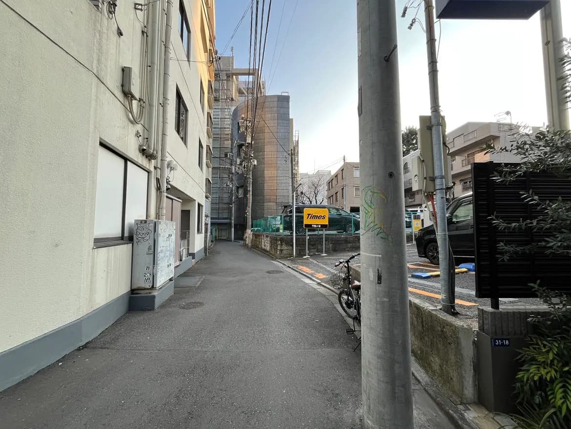 日本の都市の狭い路地、建物と植栽、クリアな青空と駐車場の看板