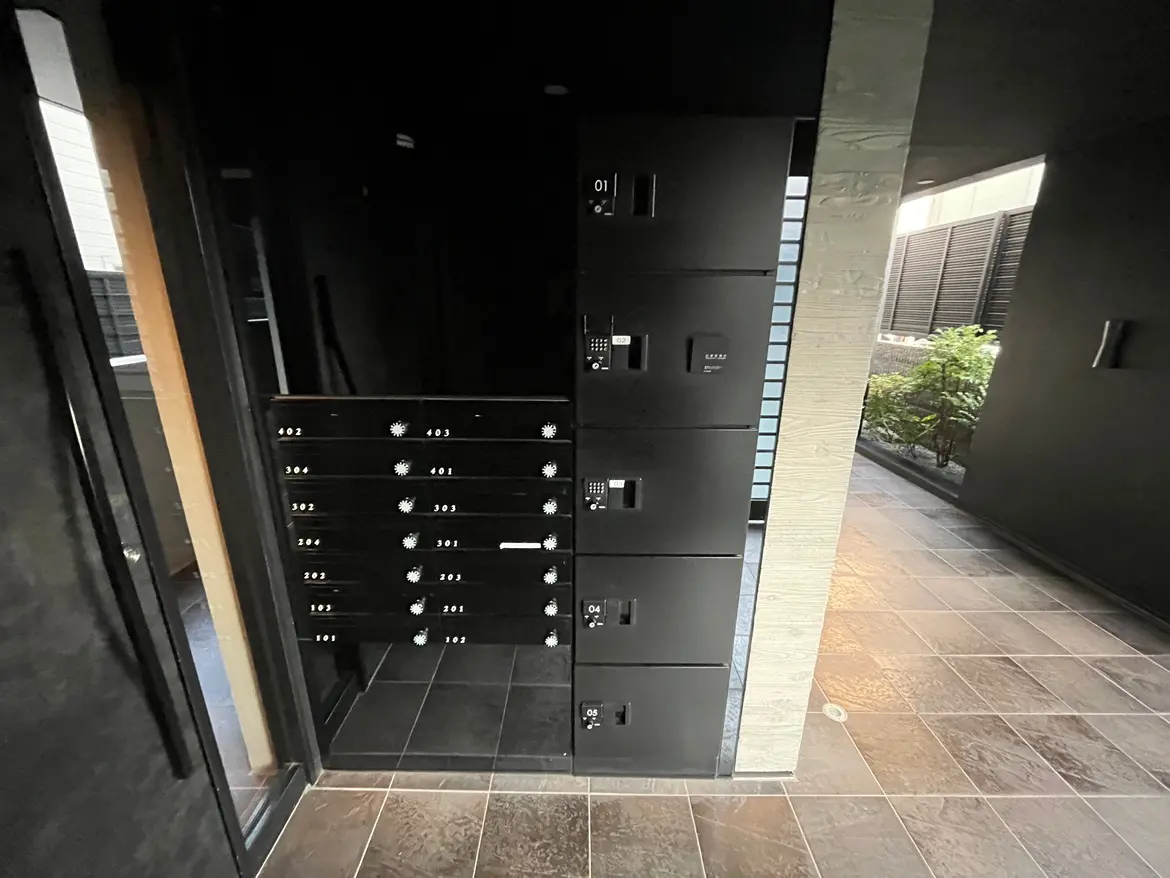 マンションのエントランスに設置された郵便受け、モダンなデザインの宅配ボックス、タイル張りの床