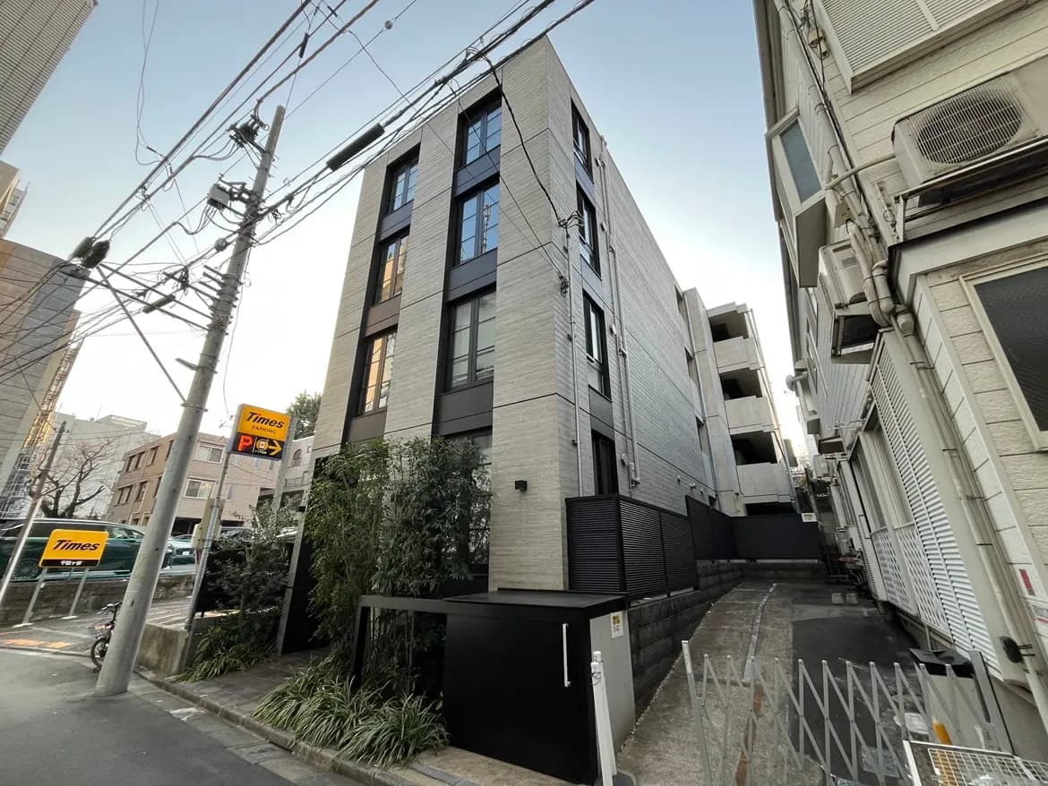 現代的なデザインの都市型マンション、電柱と電線が周囲にある風景、Timesの駐車場サインが目立つ