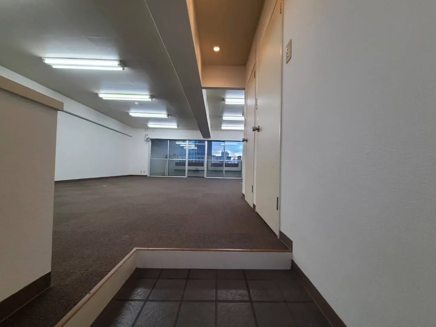 広々としたオープンフロアプランのオフィススペース、天井埋め込み型の照明