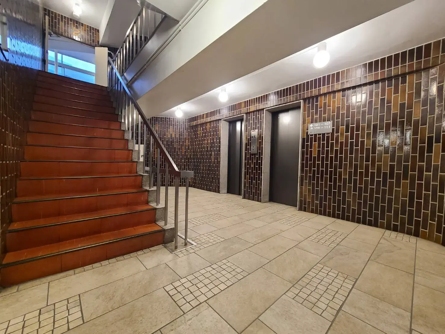 タイル貼りのエントランスホールと木製の階段