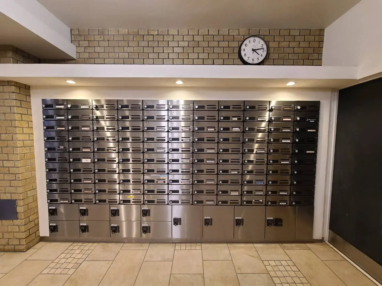 清潔で整理された共用ポストエリア、壁掛け時計付き