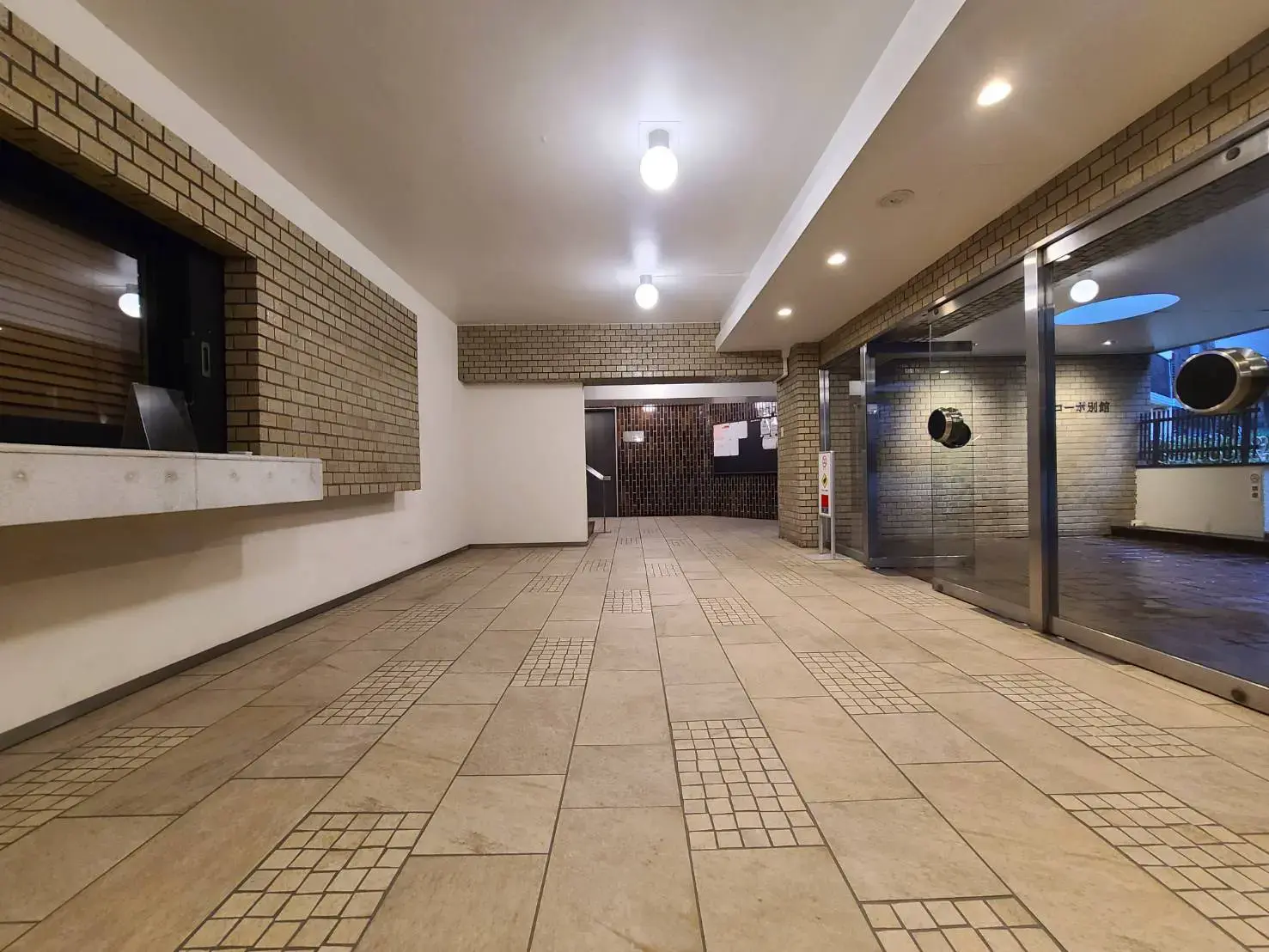 照明が明るいタイル貼りのエントランスホール