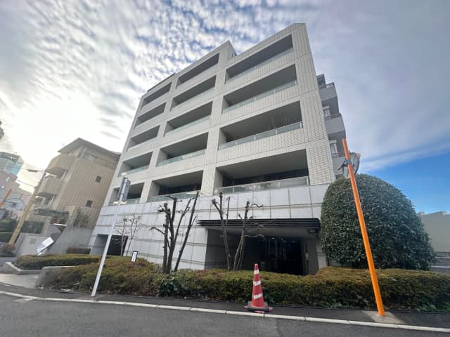 現代的なデザインのマンション外観、白い壁と大きな窓、青空と雲を背景にした都市の風景