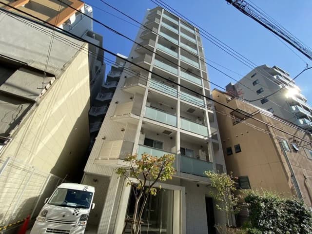 - 都市部に立つ現代的なマンション、ガラスバルコニーと緑の植栽を備えた外観、晴れた青空の下で撮影された一コマ