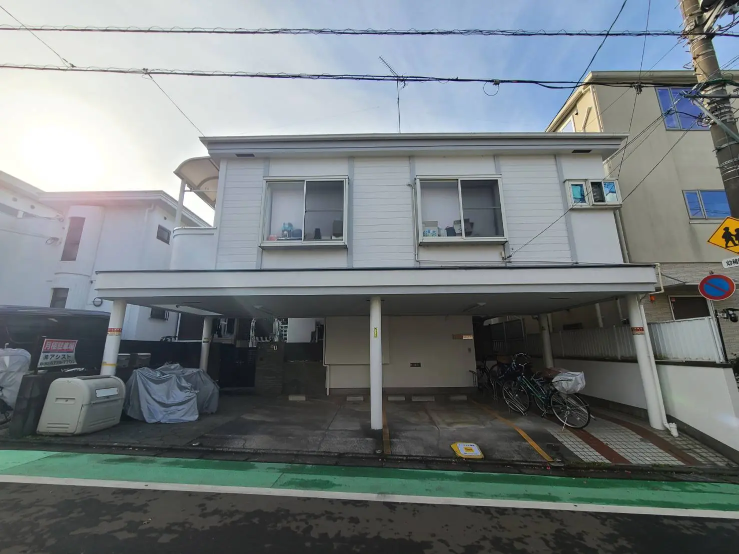 駐車スペース付きの現代的な二階建て住宅、自転車が並ぶ屋根付き駐輪場、市街地に位置