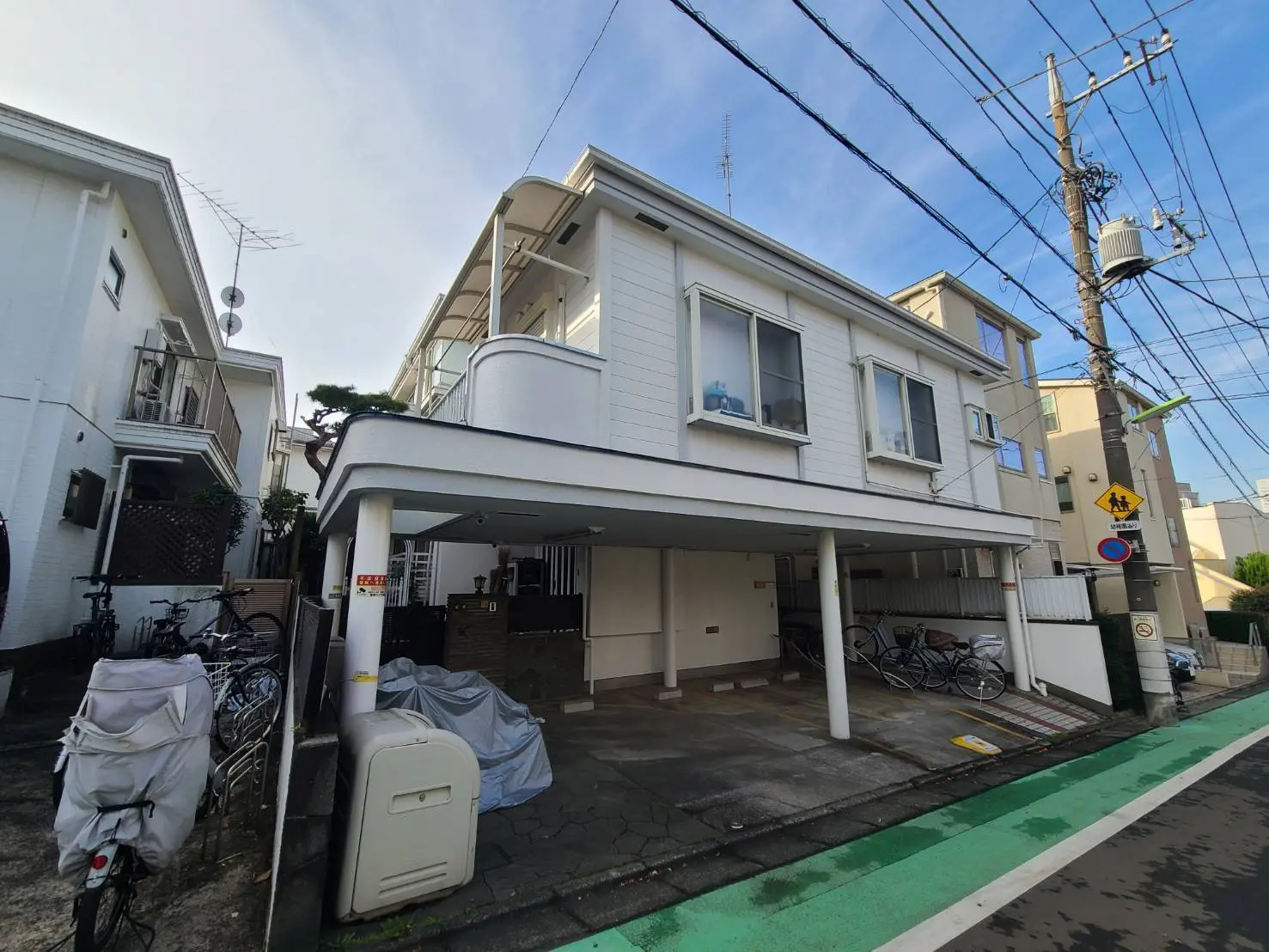 都市型の住宅街にあるモダンな二階建ての家、駐車スペースと自転車置き場がある外観
