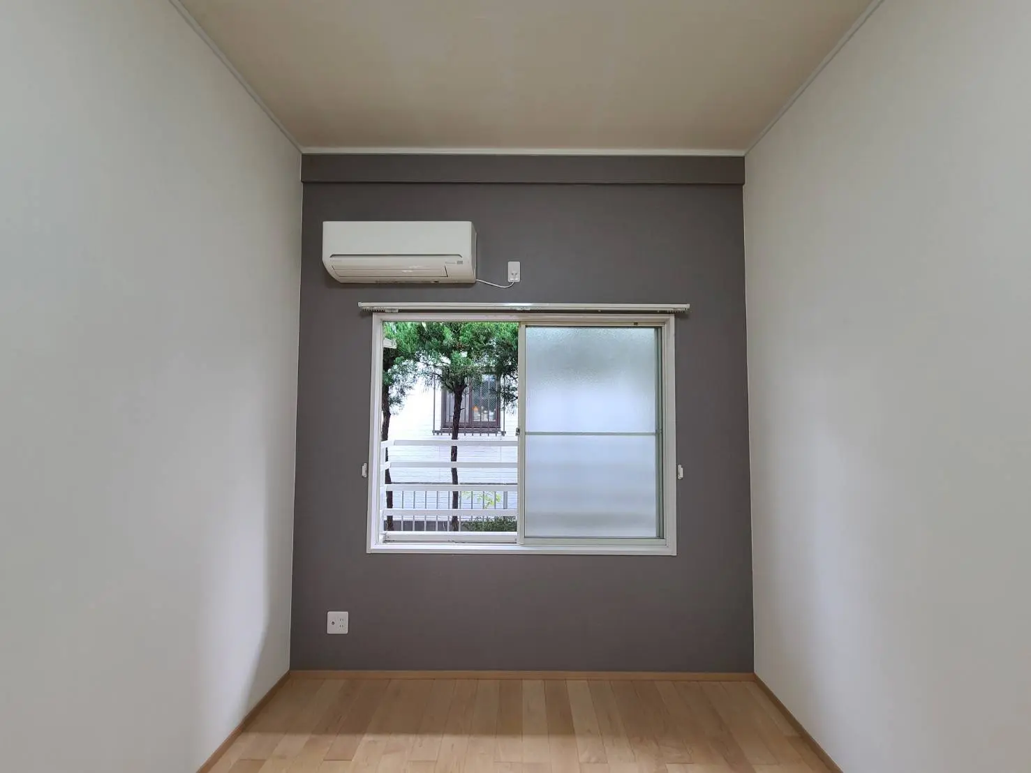 シンプルなデザインの空の部屋、グレーの壁と木製のフローリング、窓にはブラインドが付いているインテリア