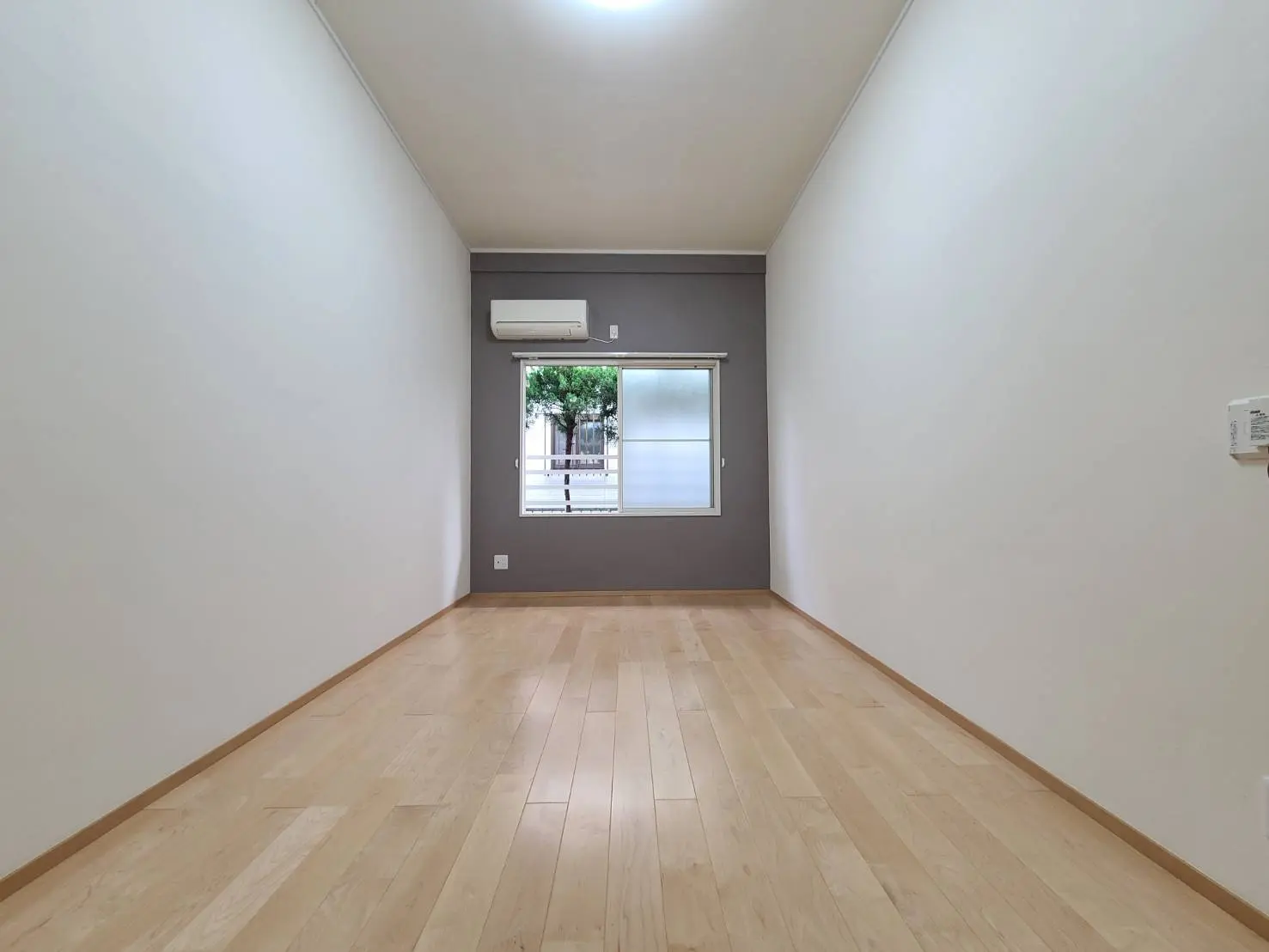 シンプルな内装の空の部屋、ナチュラルな木製のフロア、白い壁、窓からの自然光