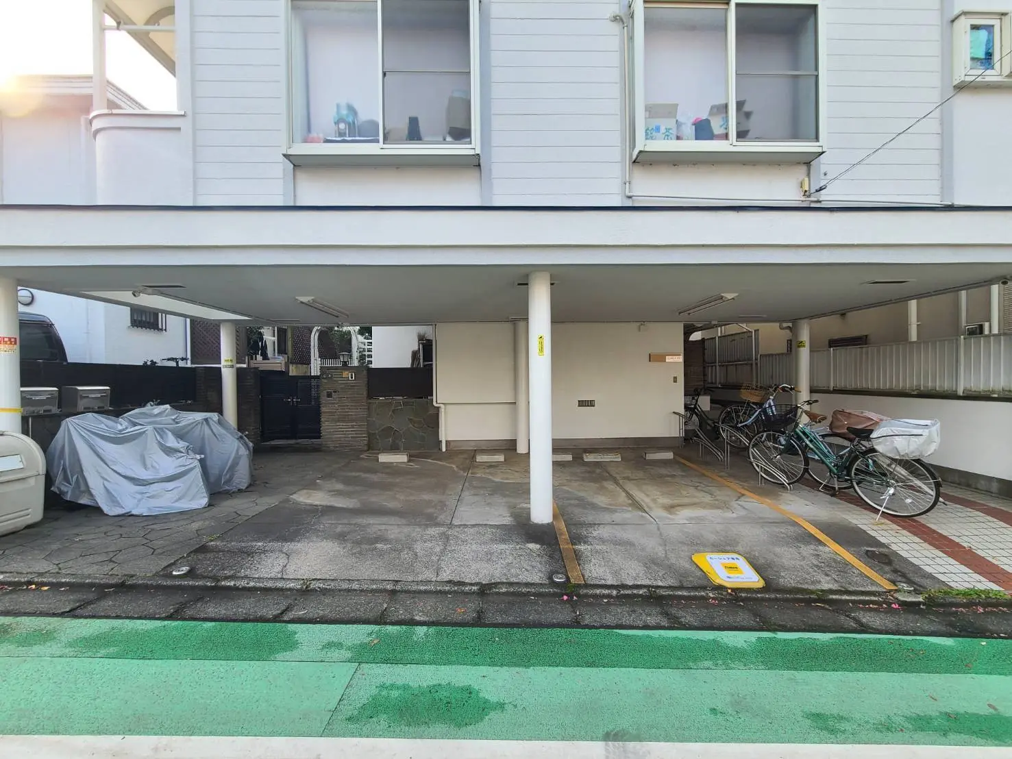 アパートの駐車場と自転車置き場、白い壁の建物とカラフルな路上ライン