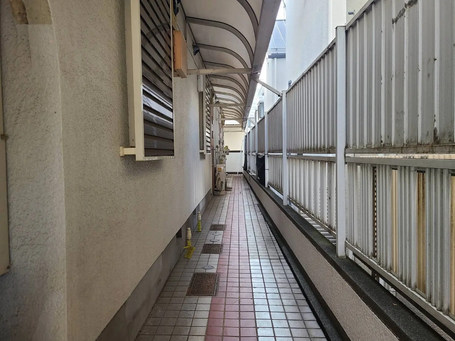 狭い都市の路地、壁とフェンスに囲まれた通路、敷石の歩道