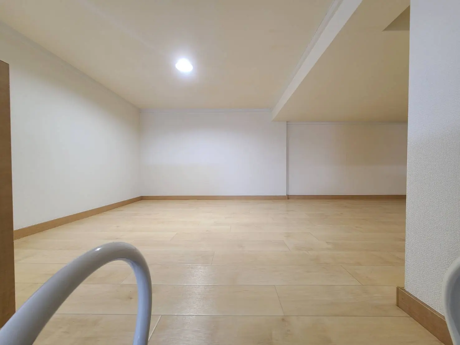 照明付きのシンプルな無垢フローリングの部屋、白い壁、広々とした空間