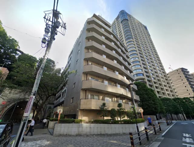 - 都会の風景に佇む低層マンションと高層ビル群、周囲には緑豊かな樹木と歩行者がいる風景