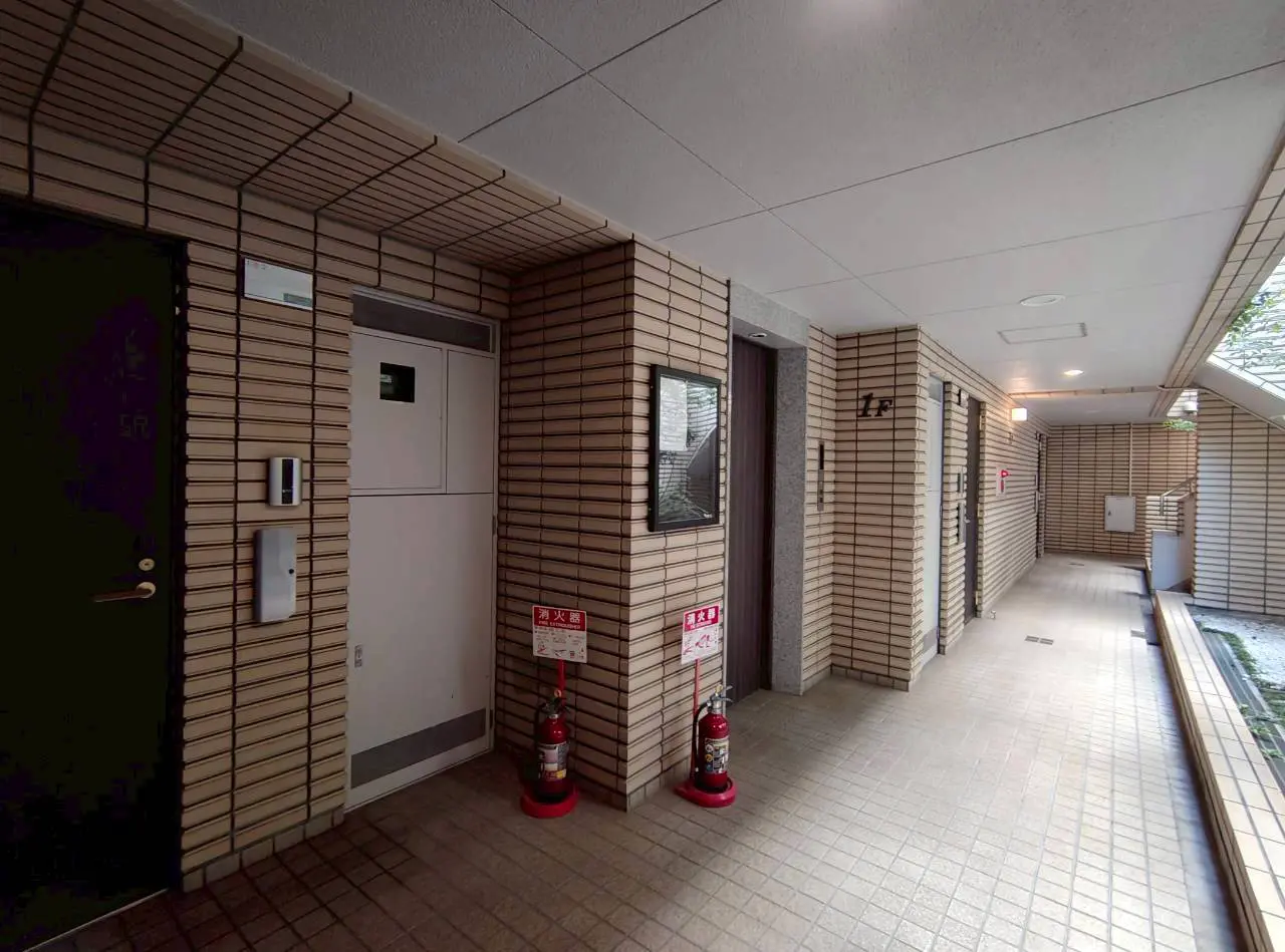 - 複数のドアと消火器が設置されたモダンな建物のエントランスホール、タイル張りの床とシンプルなインテリアデザイン