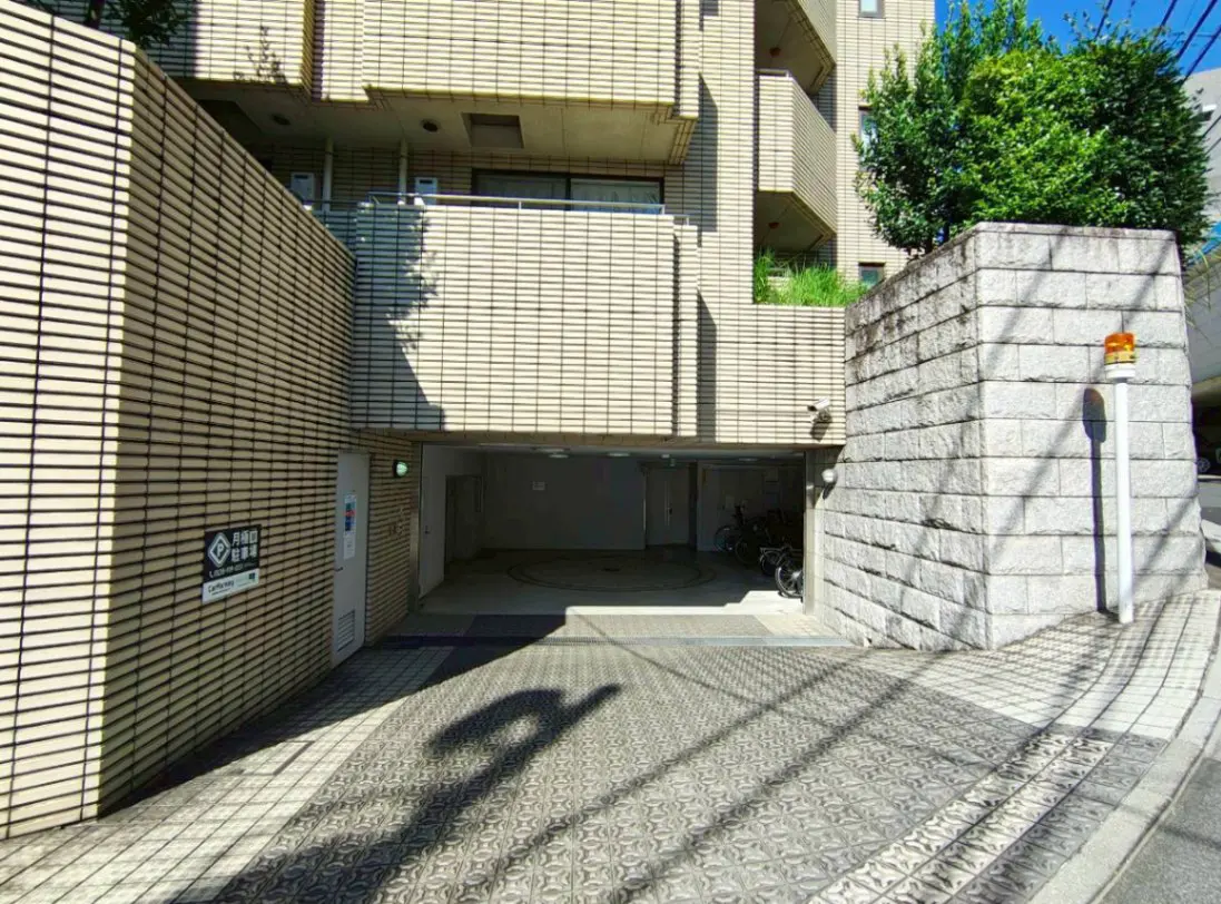 - 現代的なデザインのマンションの駐車場入口、ブロック壁と植栽がある外観の写真