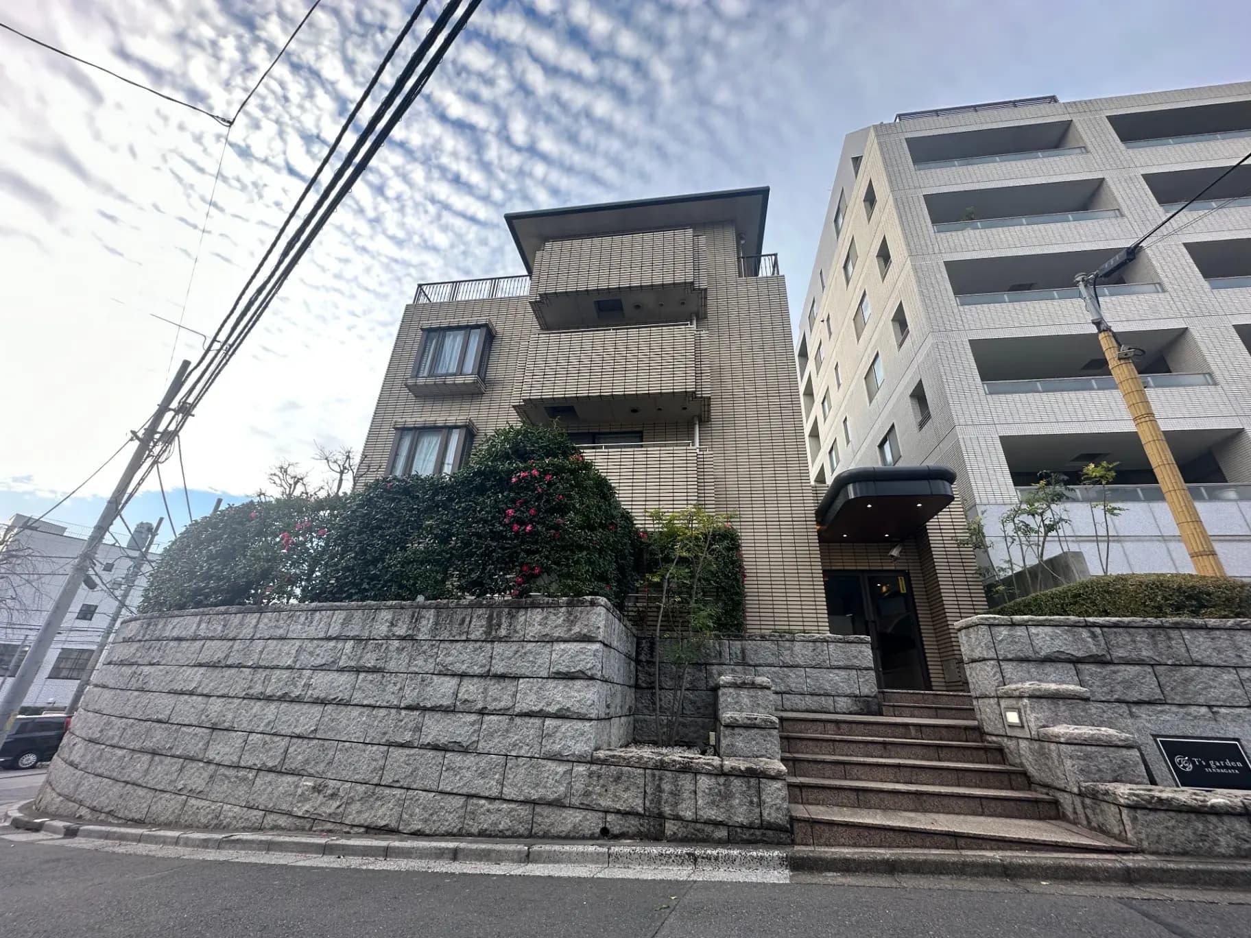 都市の角にあるモダンなマンション、石造りの壁と階段、花を植えた緑豊かな景観