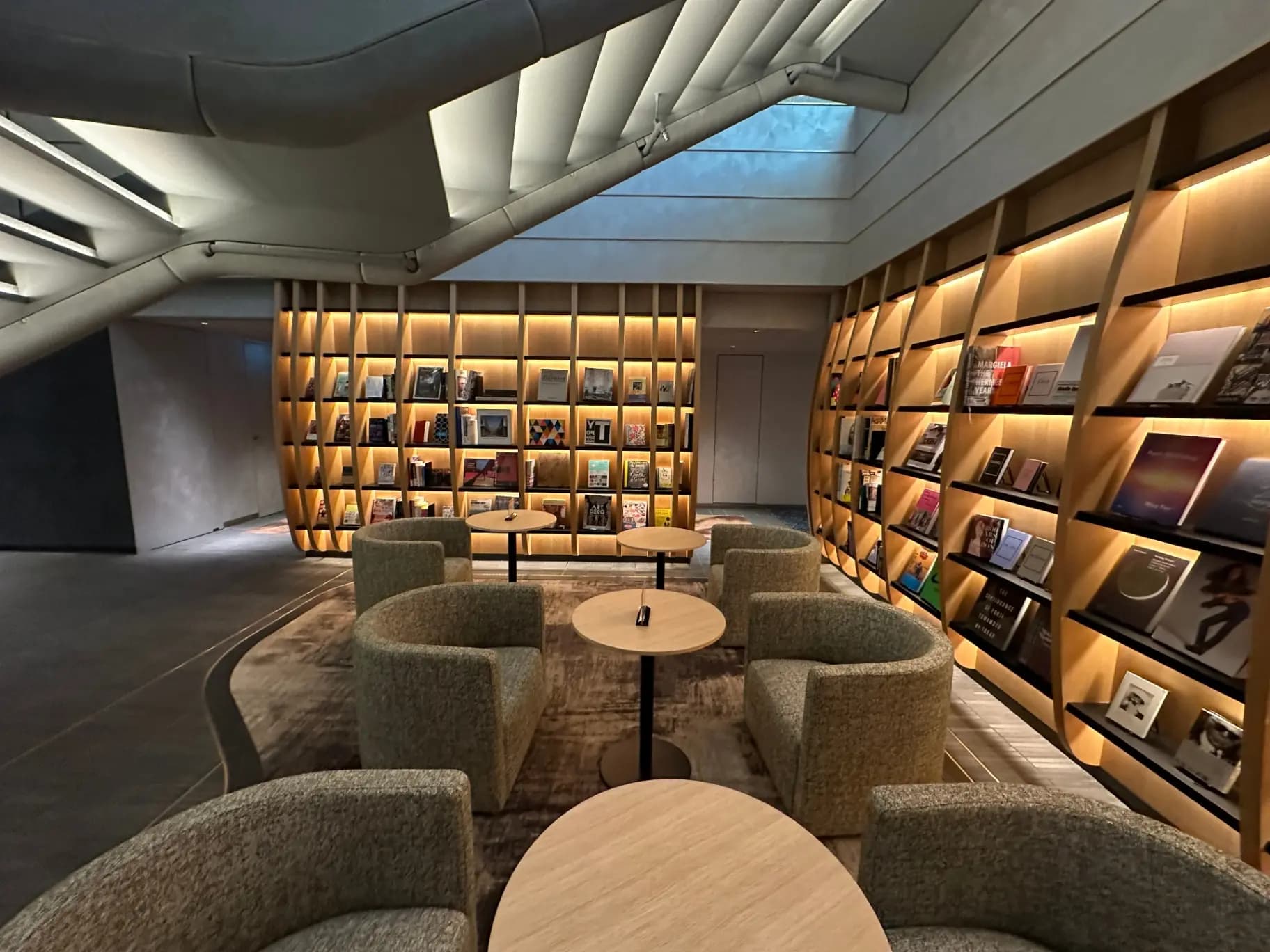 スタイリッシュな図書館の内装、壁一面の本棚とリラックスできるソファセット、モダンな照明とデザインの空間