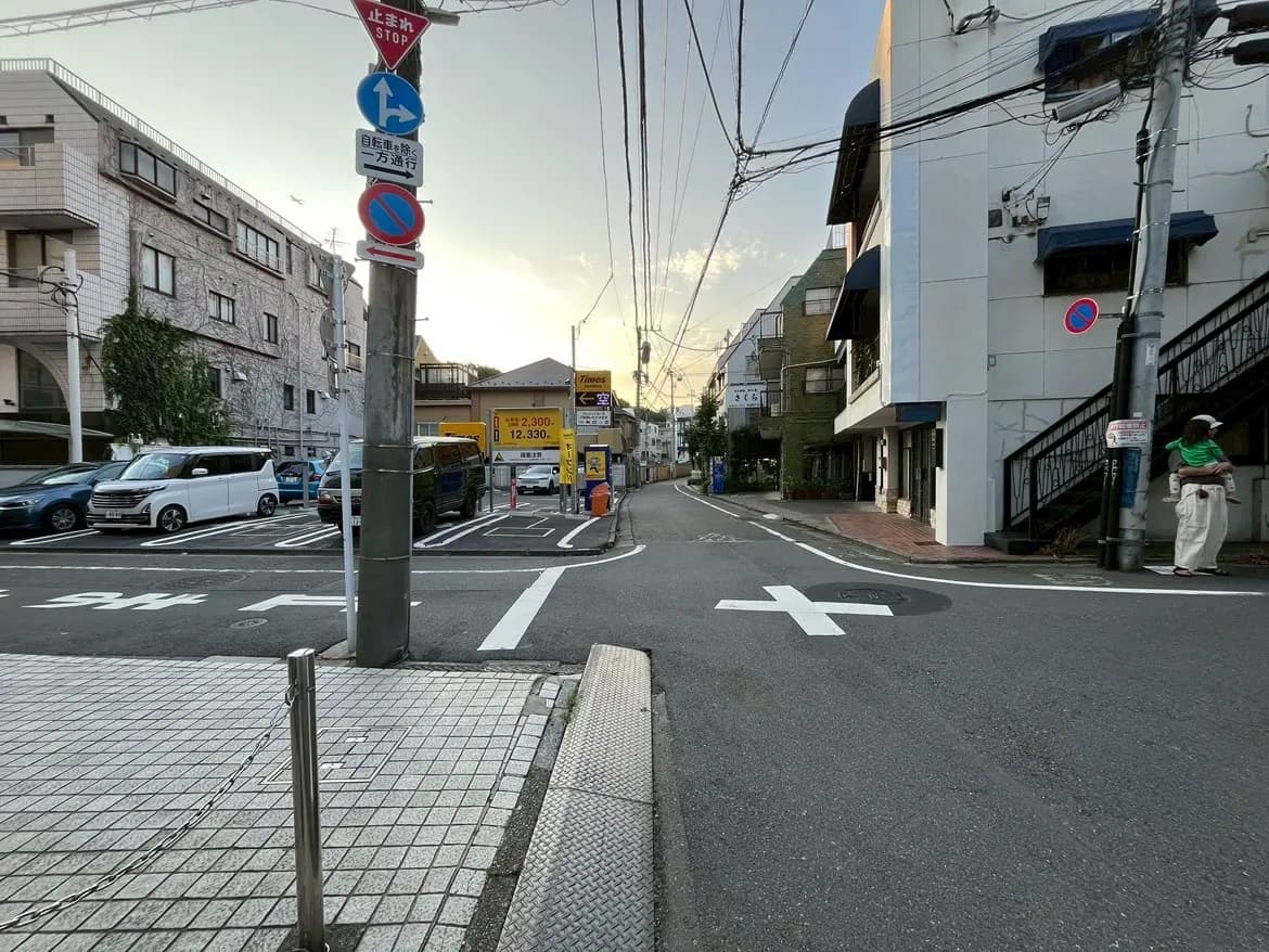 - 地元の住宅街の交差点、車が停車している駐車場、街灯と交通標識が並ぶ夕暮れ時の風景