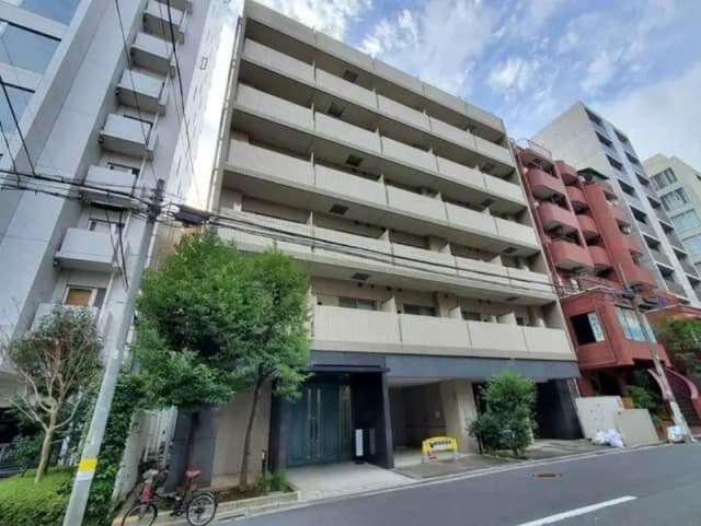 - 現代的な外観のマンション、周囲に緑豊かな樹木と他の建物がある街並みの風景