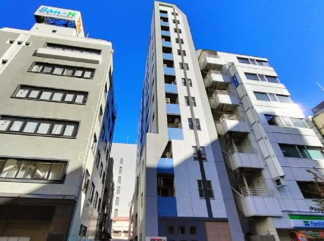 - 青空の下、隣接した高層ビル群の外観、アクセントカラーの壁面を持つ建物とバルコニーが特徴的な景観