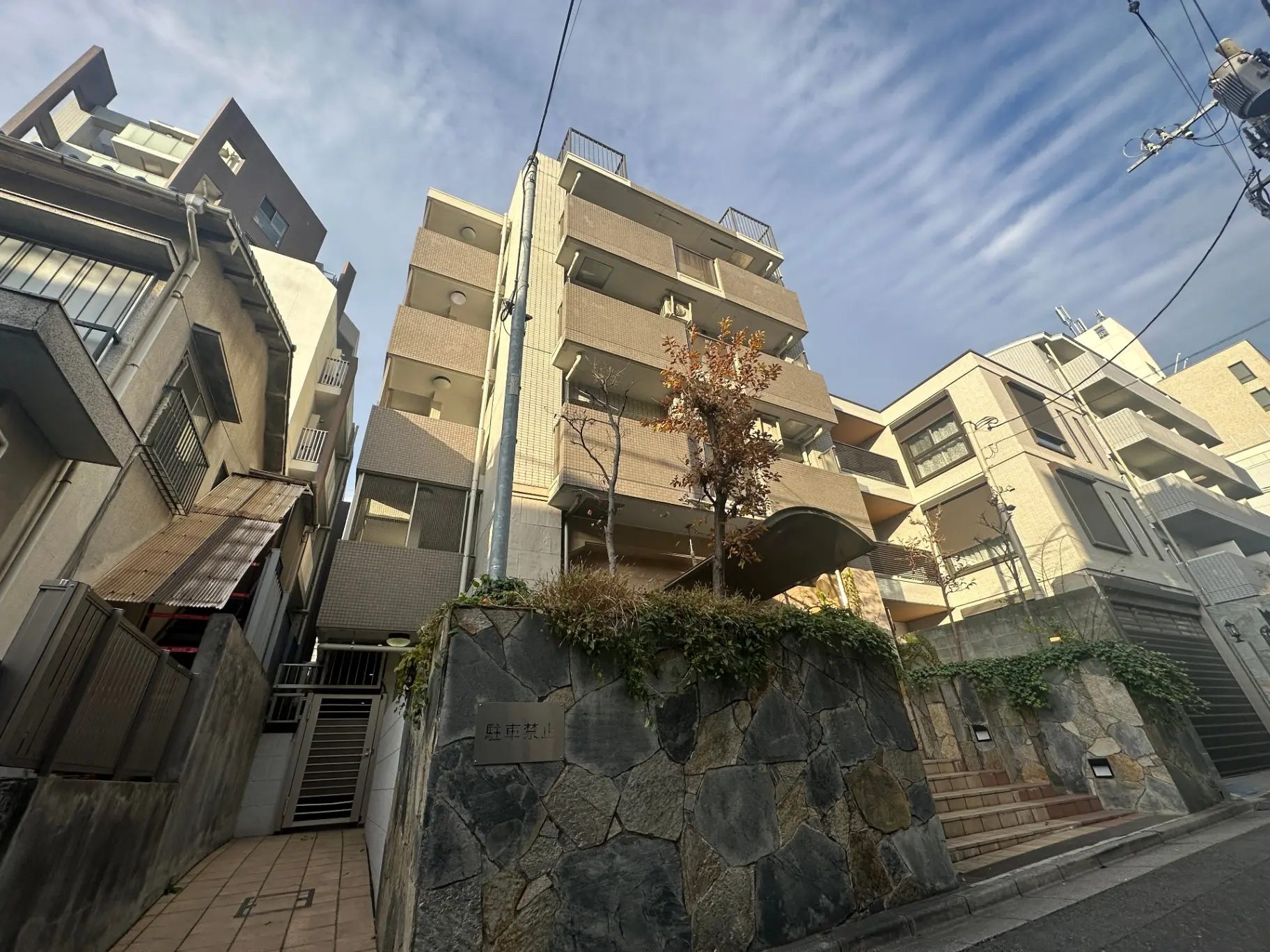日本の都市部に建つ複数階建てのアパート、晴れた日の青空と石造りの壁