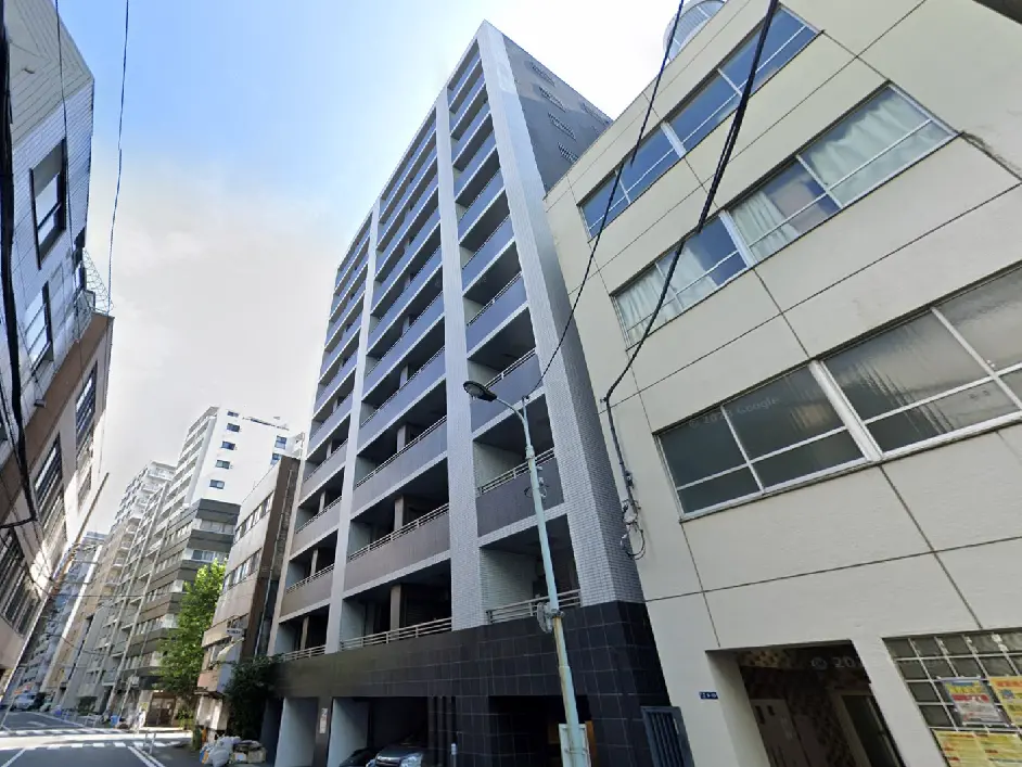 - 都市の中に立つ現代的なマンションビル、周囲には他の建物が並ぶエリアの様子