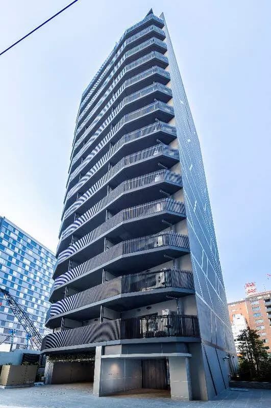 - モダンなデザインの高層マンション、バルコニーが特徴的な外観、青空を背景にしたビルの印象