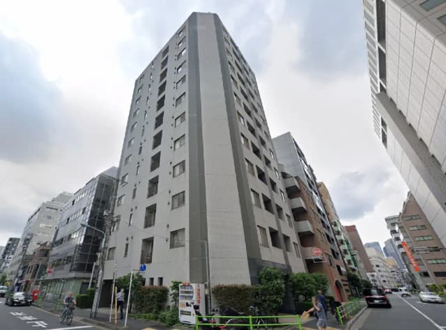 - 都市のビル群に囲まれた近代的な高層マンションの外観、周囲には歩行者や車両が行き交う風景