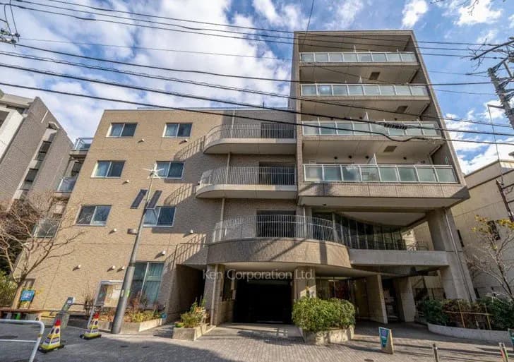 現代的なマンションの外観、バルコニー付きの多階建て建物、青空と電線が見える都市の住宅風景