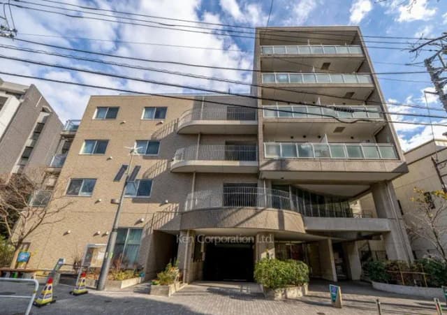 現代的なマンションの外観、バルコニー付きの多階建て建物、青空と電線が見える都市の住宅風景