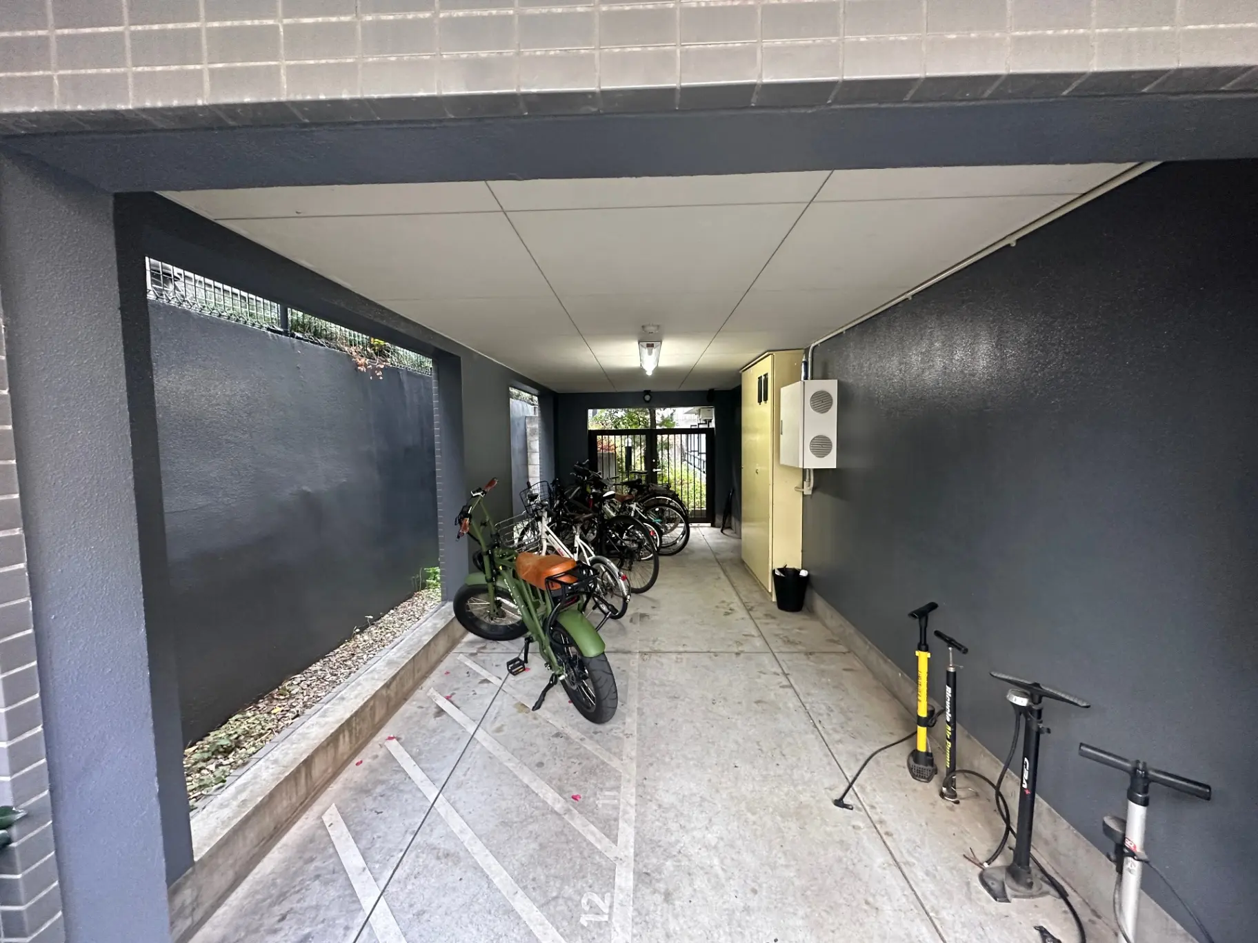 建物内自転車駐輪スペース、防犯カメラとエアポンプ装備、整然と並んだ複数の自転車