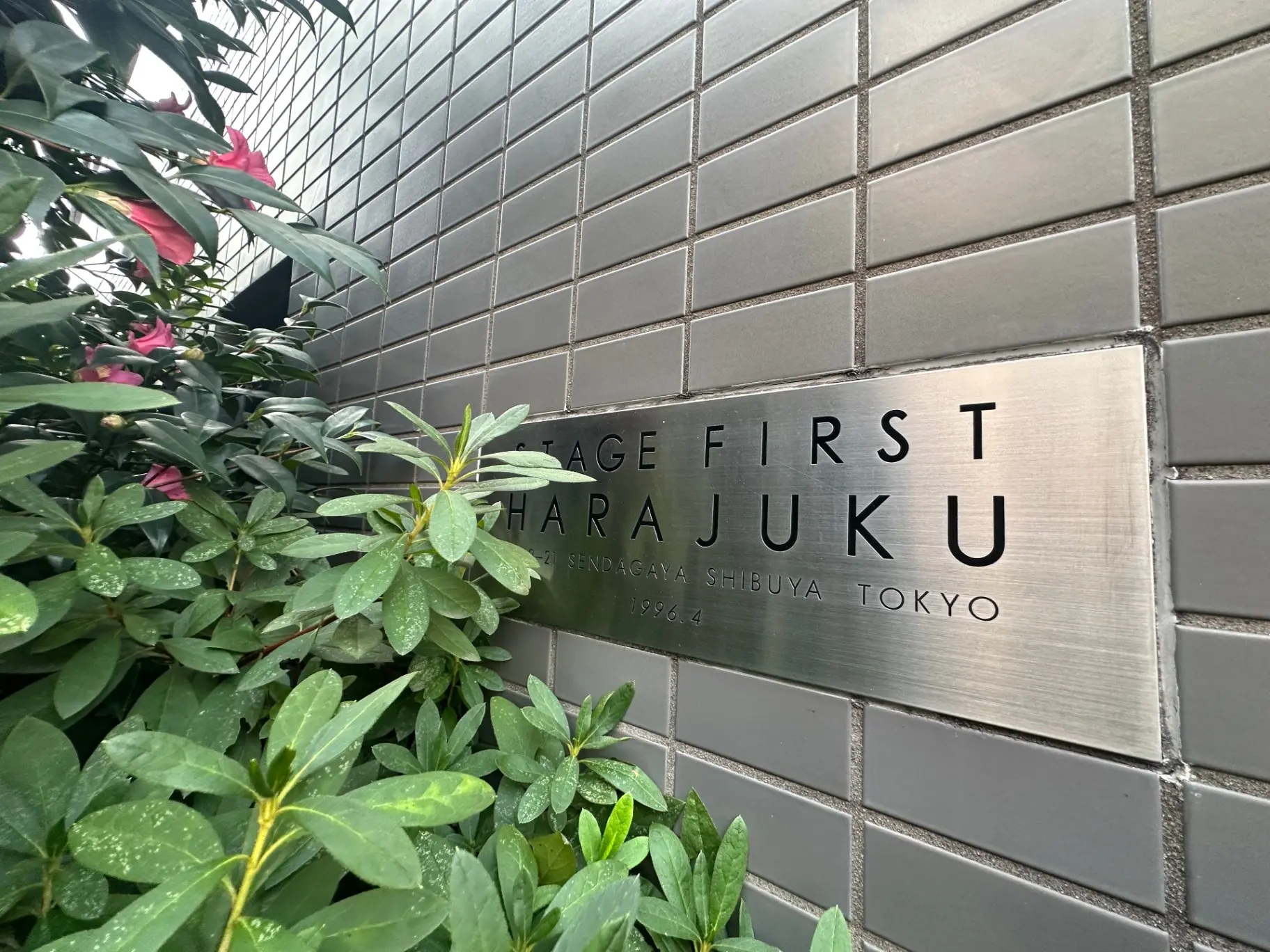 原宿の建物のエントランスサイン、緑の植物とタイル張りの壁