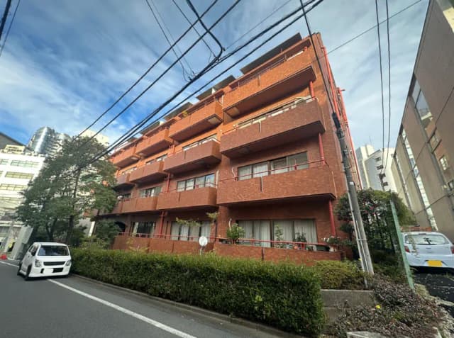 都市の環境にある赤レンガ造りのアパート建物、晴天の下で路上に駐車しているホワイトカー