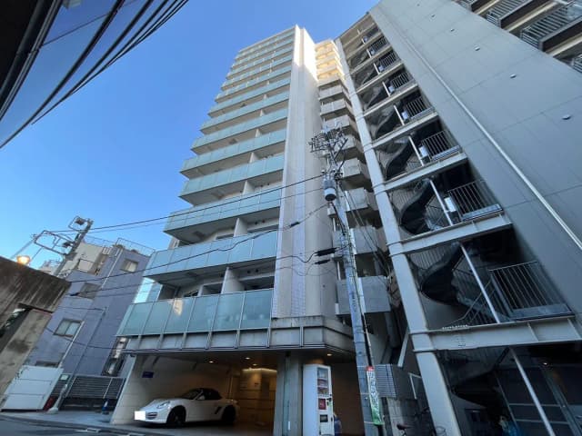 - モダンな高層マンションの外観、クリアガラスのバルコニーが並び、青空をバックにした夕暮れ時の様子