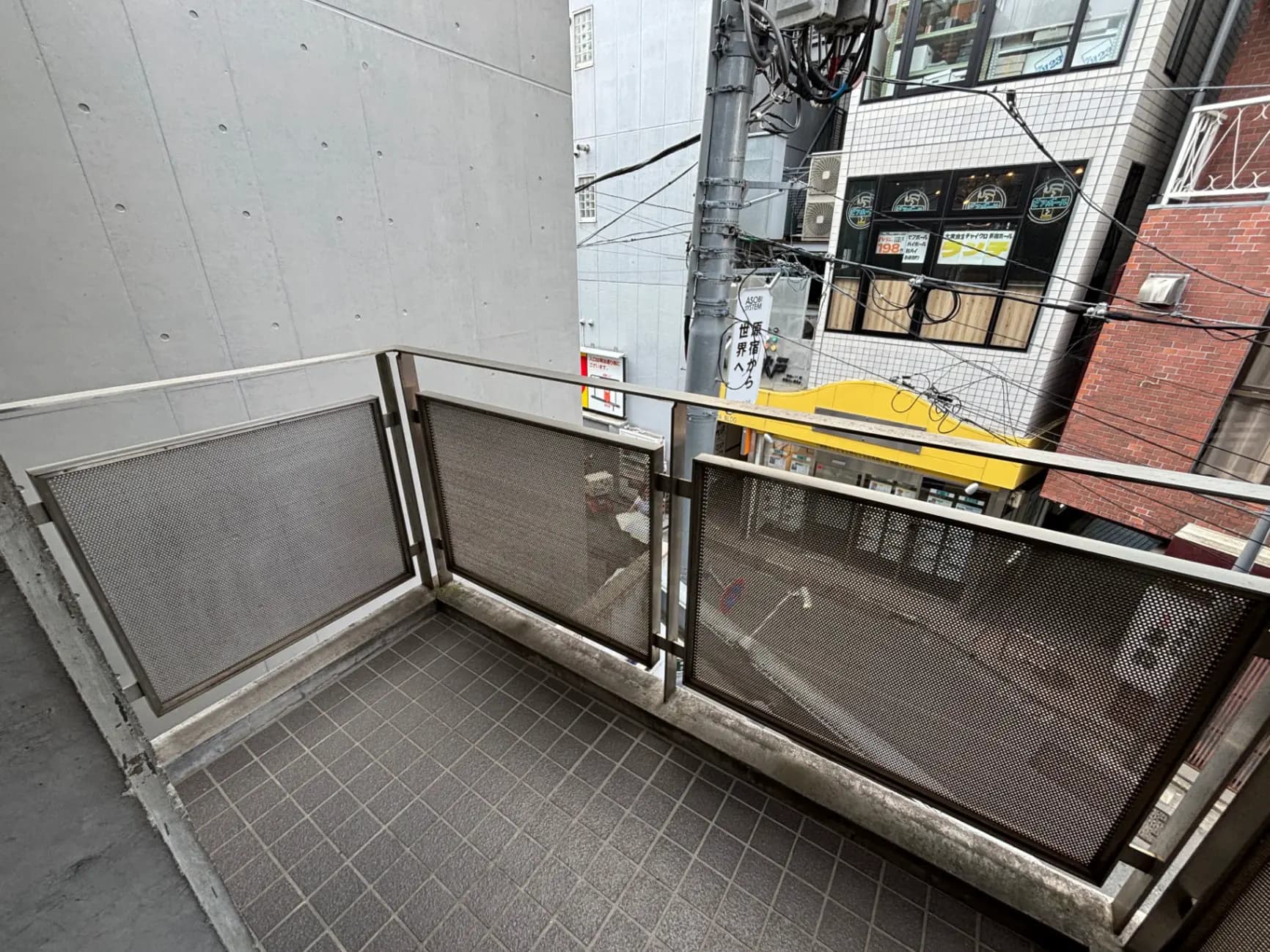 - 都市の景色を望むバルコニー、メッシュの手すりとタイル張りの床のシンプルなデザイン