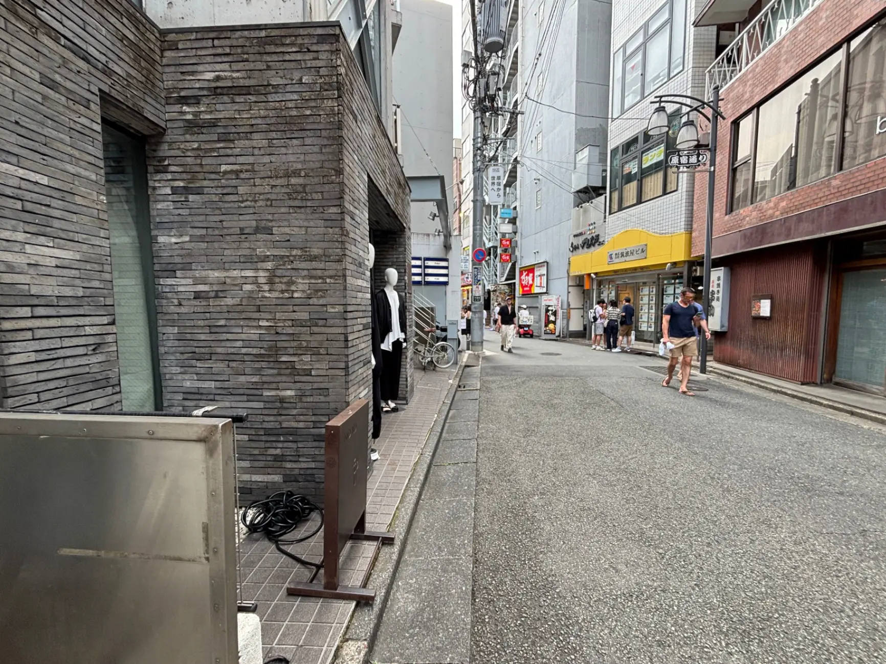 - 現代的な街並み、コンクリートとレンガで造られた建物、通行人が行き交う賑やかな街の様子