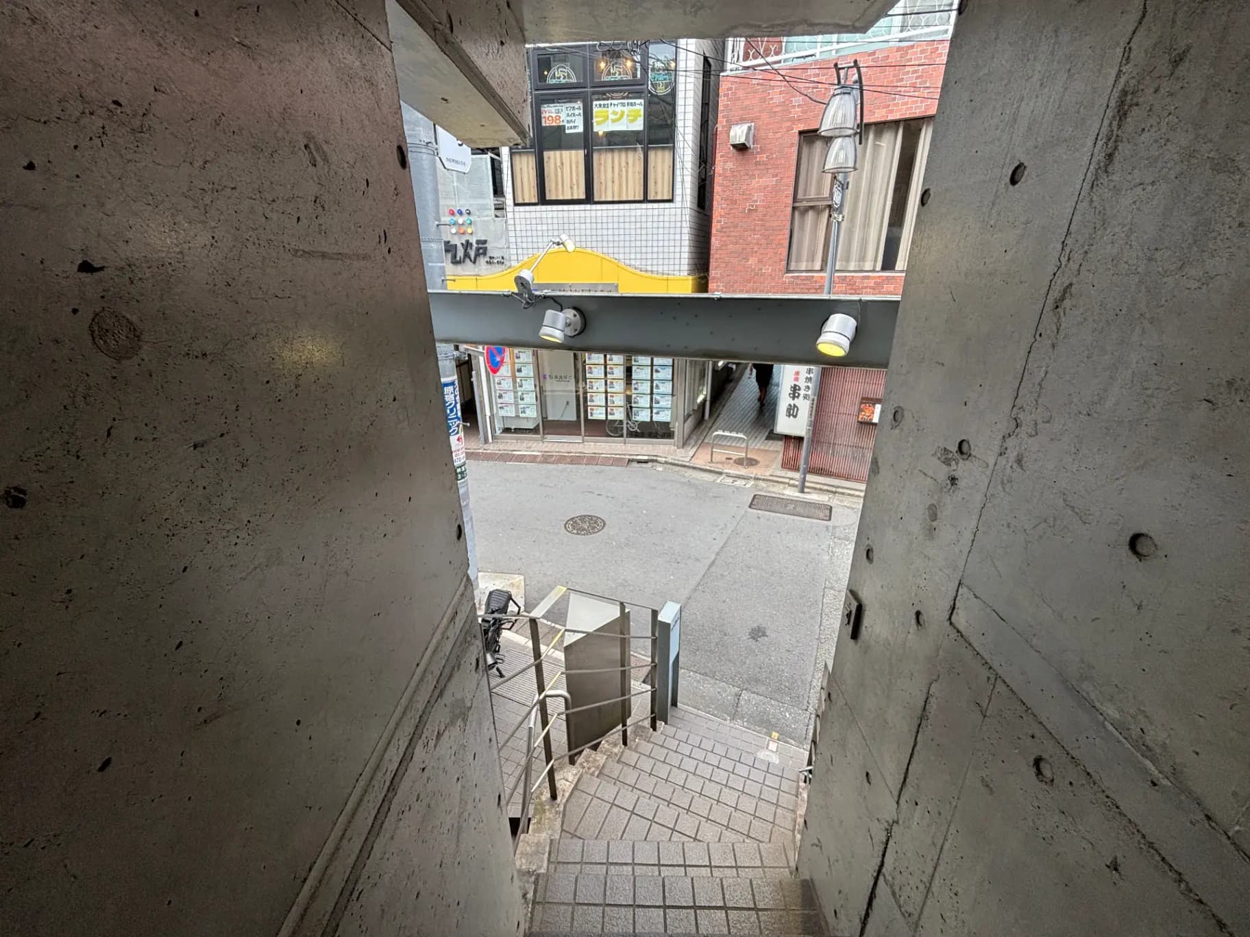 - 螺旋階段から見た外の通り、周囲には店舗や商業施設が並ぶ都市の風景