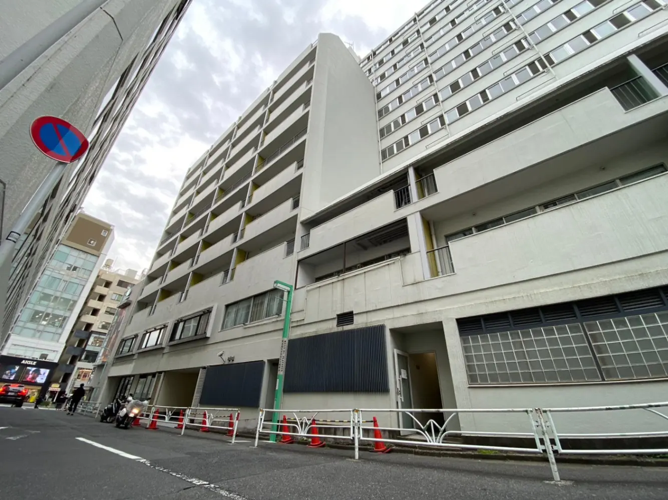 都市の通りに面した現代的な建物の外観、駐車場入口、幹線道路、雲がかかる空