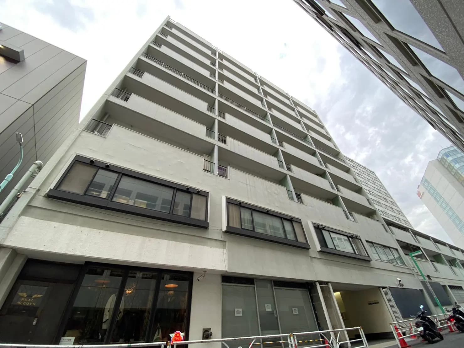 現代的な外観の都市型マンションビル、ガラス窓とベランダが特徴的なファサードデザイン