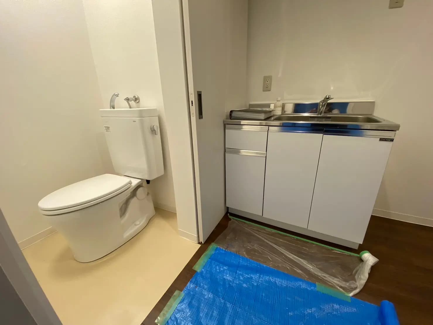 シンプルなデザインのトイレと洗面台、クリーンな室内設備と木目調フローリング