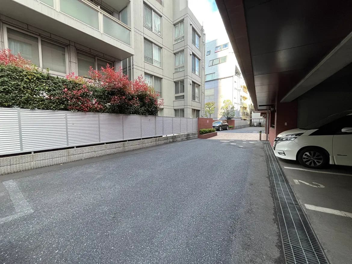 - 駐車場と建物の外観、フラワーガーデンが配されたエントランス周辺の様子。