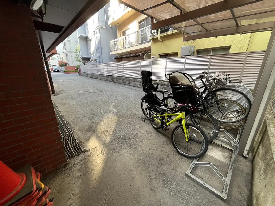 自転車の駐輪スペース、黄色い自転車と子供用のチャイルドシート付き自転車が並ぶ路地の風景